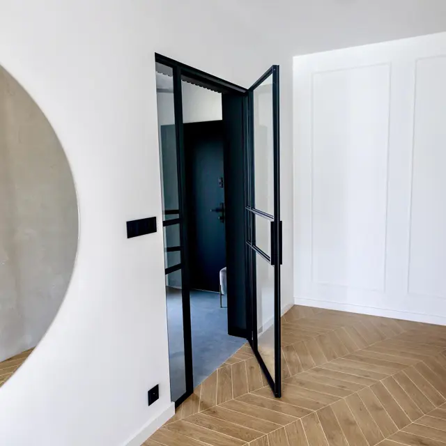 Dark aluminium door in a panelled interior